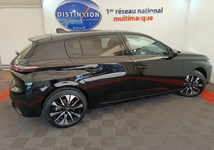 Profil droit d'une Peugeot 308 noire 2026 avec jantes alliage et vitres teintées en intérieur showroom.