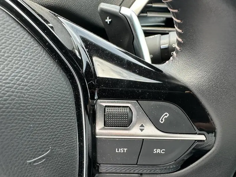 Gros plan sur les commandes noires du volant cuir à droite du Peugeot 3008 Hybride Rechargeable 2024.