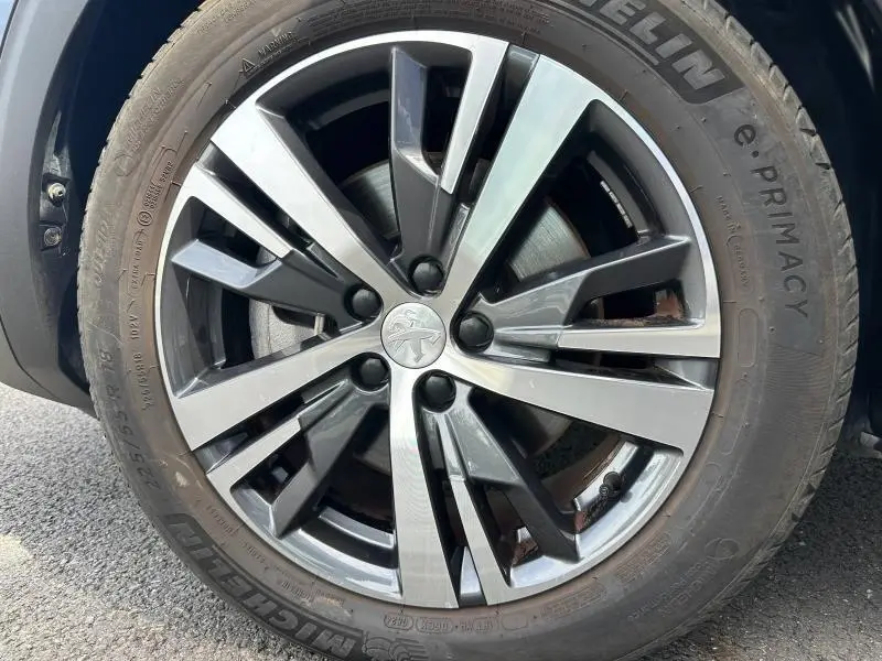 Gros plan sur la jante alu bicolore du côté avant droit du Peugeot 3008 Hybride Rechargeable noir Perla Nera.