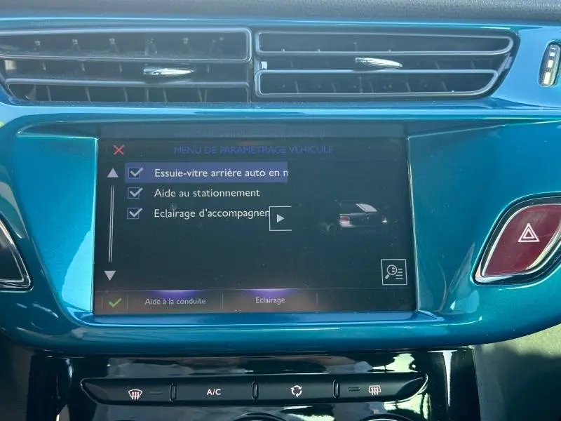 Écran tactile central bleu turquoise montrant le menu de paramétrage véhicule avec options d’aide à la conduite.