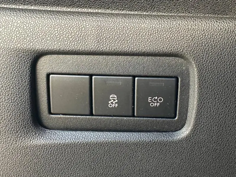 Gros plan sur les boutons de commande noirs du tableau de bord intérieur d'une DS3 noire, affichant les fonctions ESP et ECO désactivées.