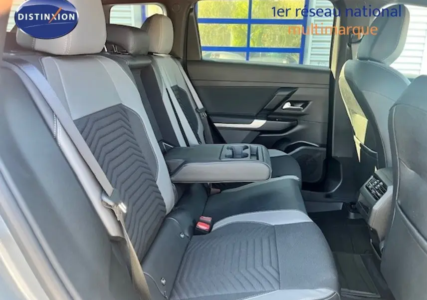 Vue intérieure arrière du Jeep Compass 2026, sièges bicolores gris clair et foncé avec accoudoir central déployé.