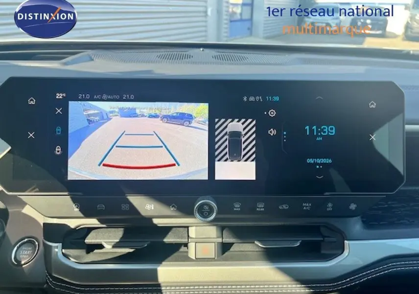 Vue intérieure du tableau de bord du Jeep Compass 2026, écran tactile affichant la caméra de recul et l'horloge digitale.