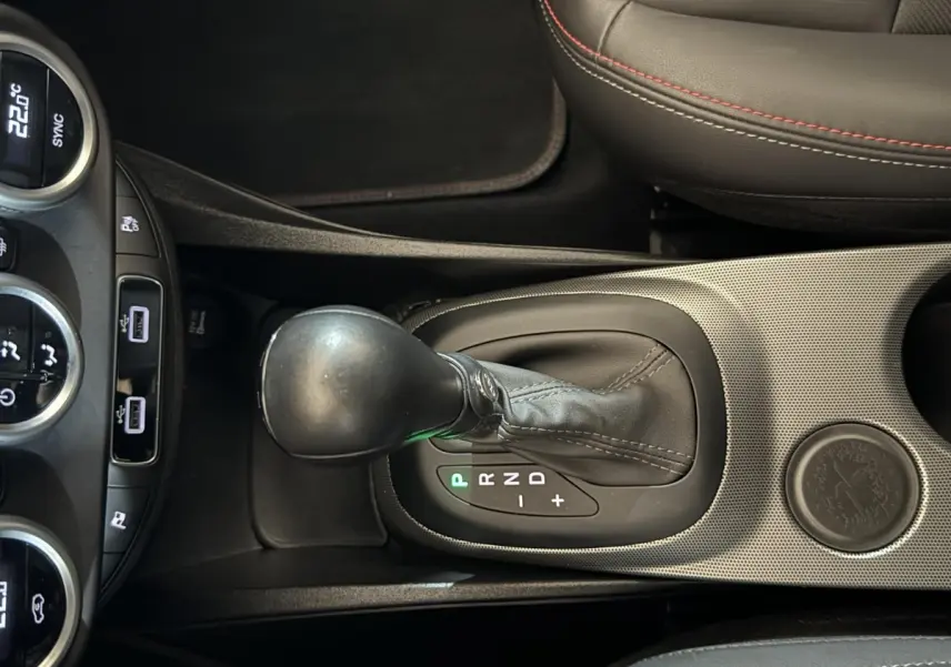 Vue rapprochée de la console centrale noire du Fiat 500X 2021, mettant en valeur le levier de vitesse automatique et les commandes climatisation.