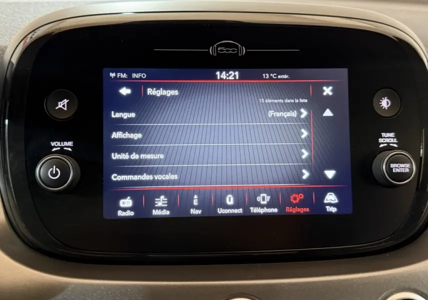 Écran tactile central de la Fiat 500X noir affichant le menu réglages avec commandes vocales en français.