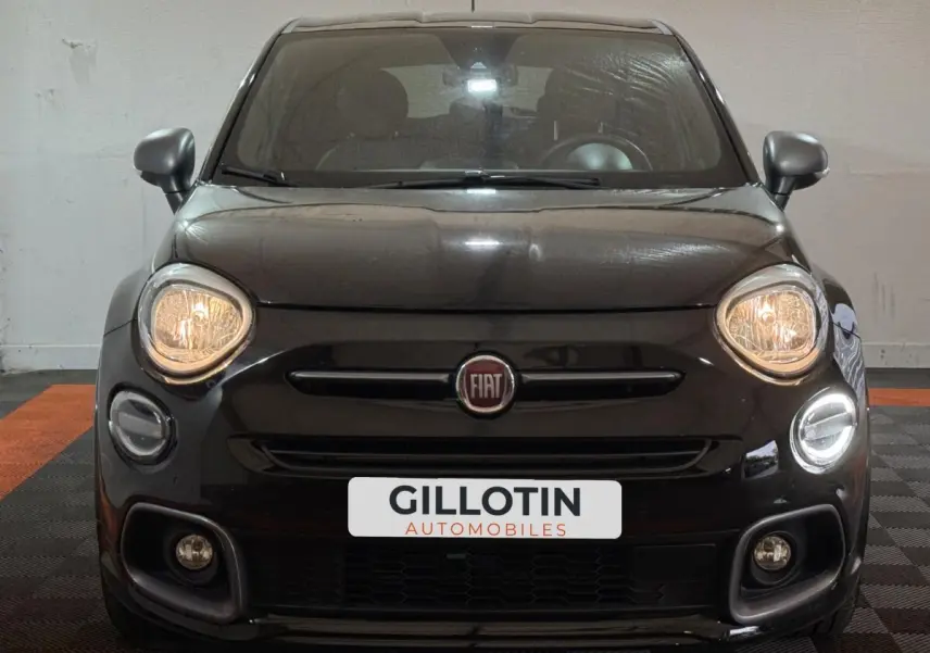 Vue frontale d'une FIAT 500X noire avec phares allumés et logo Fiat centré sur la calandre.