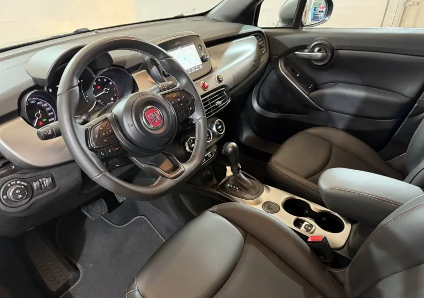 Vue intérieure côté conducteur du Fiat 500X 2021 avec tableau de bord noir et écran tactile central.