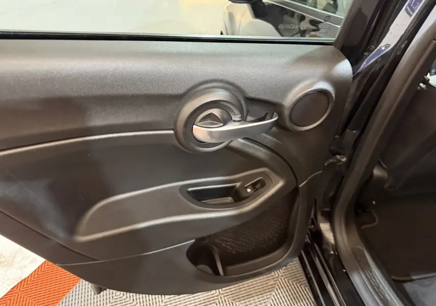 Gros plan sur la porte arrière gauche noire de la FIAT 500X 2021 avec poignée argentée et haut-parleur intégré.