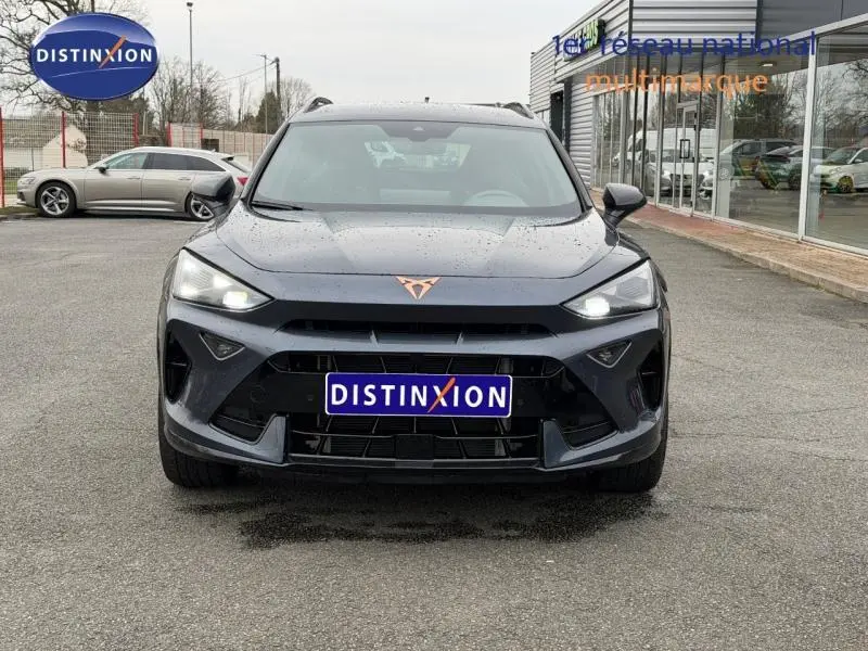 Vue frontale d'un CUPRA Formentor 1.5 eTSI Hybrid gris Graphène avec logo cuivré et calandre imposante.