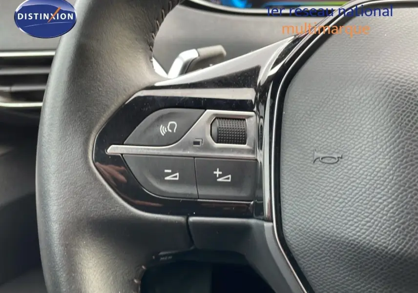 Gros plan sur le volant noir du Peugeot 3008 2024, montrant les commandes audio et de volume à gauche.