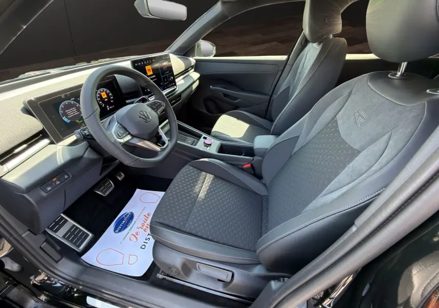 Vue intérieure côté conducteur du Volkswagen T-Roc noir ébène 2026, mettant en valeur le tableau de bord numérique et les sièges R-Line en tissu et cuir.