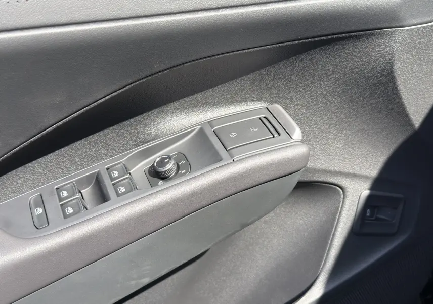 Gros plan sur la commande des vitres et rétroviseurs côté gauche intérieur noir du Volkswagen T-Roc 2026 R-Line.