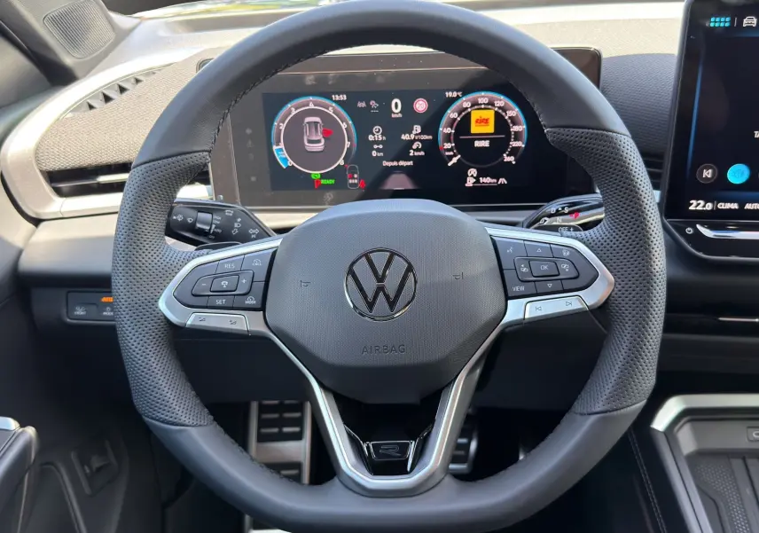 Vue rapprochée du volant noir perforé du Volkswagen T-Roc 2026 avec tableau de bord numérique et commandes intégrées.