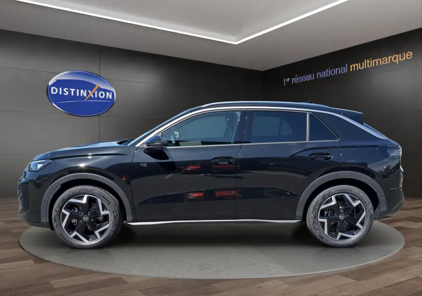Vue latérale droite du Volkswagen T-Roc noir ébène 2026 en finition R-Line avec jantes alliage et attelage visible.