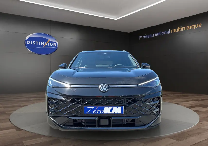 Vue frontale d'un Volkswagen T-Roc noir ébène 2026 en finition R-Line avec calandre distinctive et phares LED allumés.