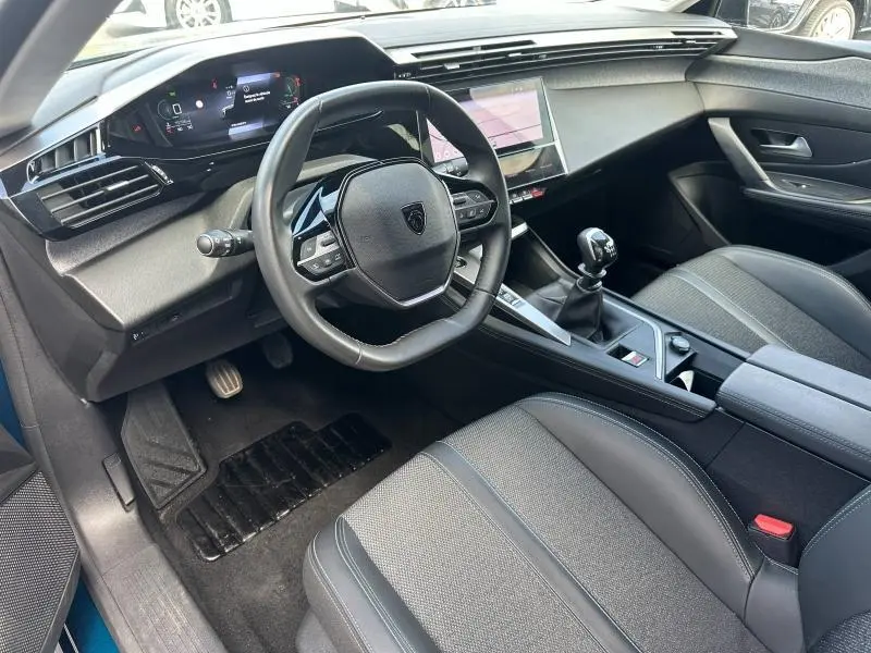 Vue intérieure côté conducteur de la Peugeot 308 2024, volant multifonction, tableau de bord digital et levier de vitesse manuel.