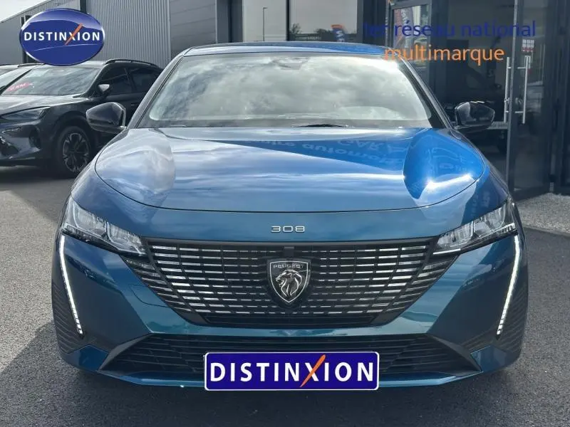 Vue frontale d'une Peugeot 308 2024 bleu Obsession avec calandre noire et feux LED verticaux distinctifs.