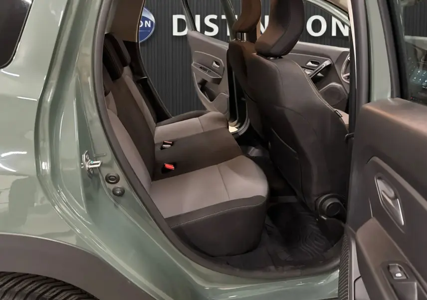 Vue intérieure côté arrière droit du Dacia Duster 2024 kaki lichen, montrant les sièges arrière en tissu gris et noir.