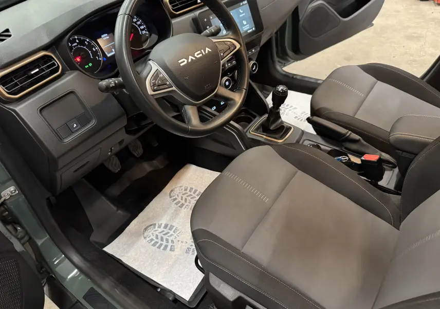Vue intérieure côté conducteur du Dacia Duster 2024 kaki lichen, avec volant multifonction, tableau de bord digital et boîte manuelle.