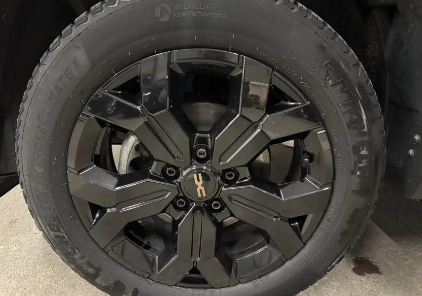 Gros plan sur la jante noire brillante et le pneu Michelin d’un Dacia Duster 2024 kaki lichen.