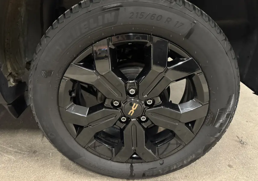 Gros plan sur la jante noire brillante du Dacia Duster 2024, mettant en valeur le pneu Michelin tout-terrain.