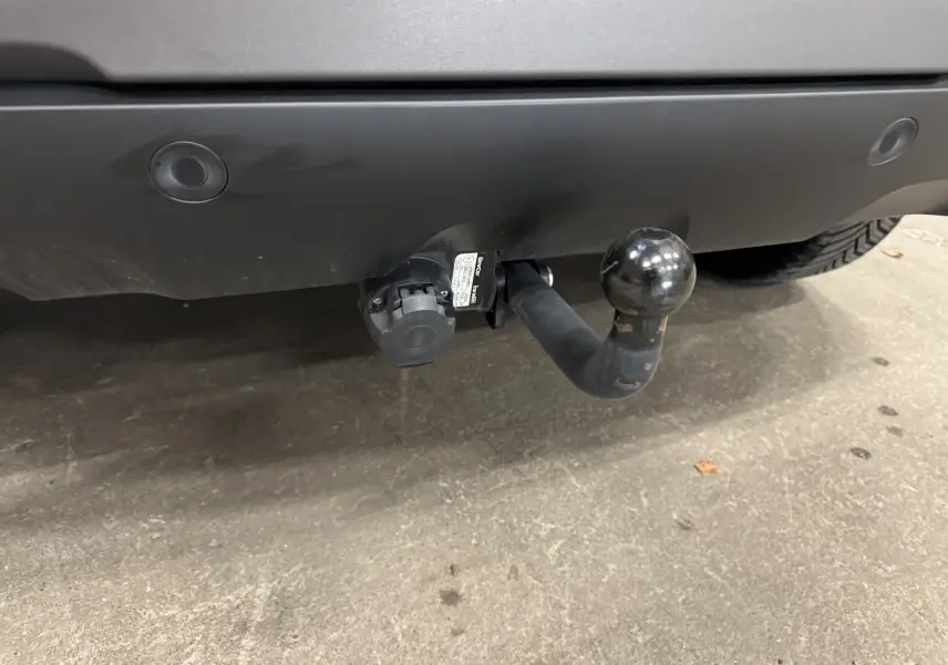 Gros plan sur l'attelage noir fixé au pare-chocs arrière du Dacia Duster 2024 couleur kaki lichen.