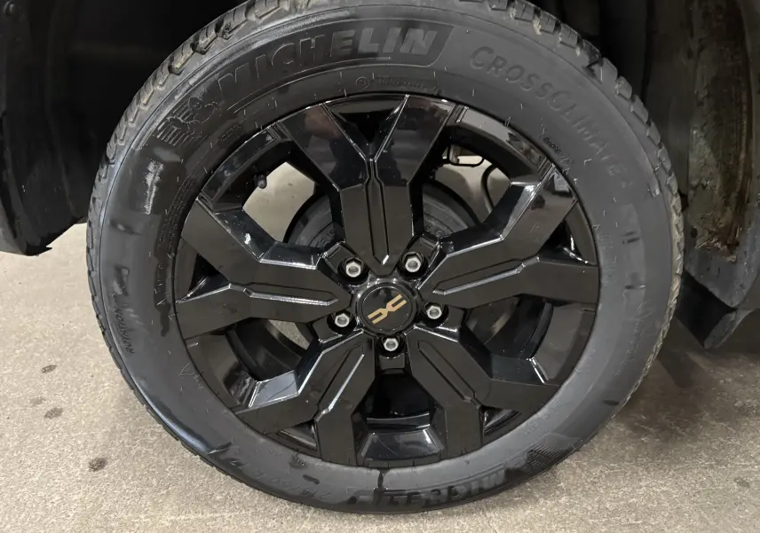 Gros plan sur la roue avant gauche du Dacia Duster 2024, jante noire brillante avec pneu Michelin CrossClimate.