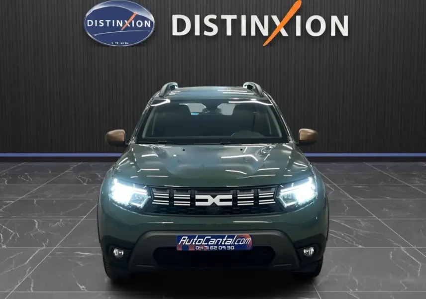 Vue frontale d'un Dacia Duster 2024 kaki lichen avec phares LED allumés et calandre noire distinctive.