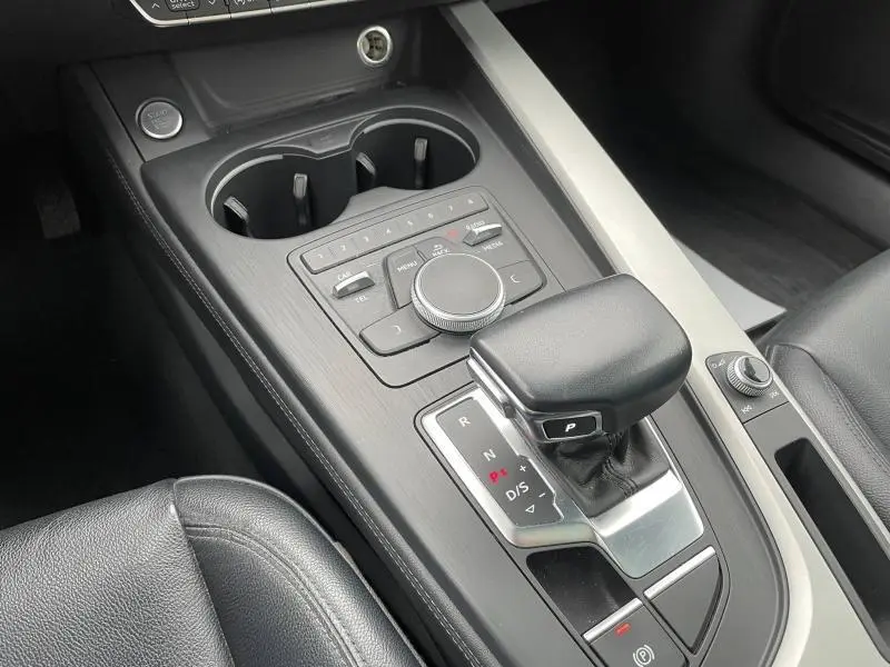 Gros plan sur la console centrale en cuir noir de l'Audi A4 Avant 40 TFSI, avec levier de vitesse automatique et commandes multimédia.