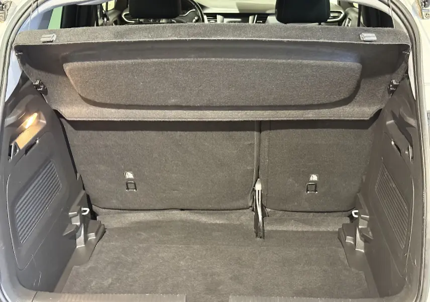 Vue intérieure du coffre ouvert d'un Opel Crossland gris 2023, montrant l'espace de chargement et la banquette arrière.
