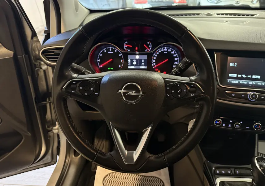 Vue intérieure centrée sur le volant noir de l'Opel Crossland gris 2023 avec tableau de bord et écran multimédia visibles.