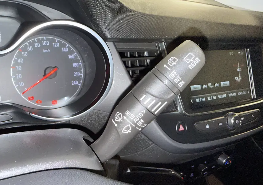 Gros plan sur la commande des essuie-glaces à gauche du volant dans l’habitacle noir de l’Opel Crossland gris 2023.