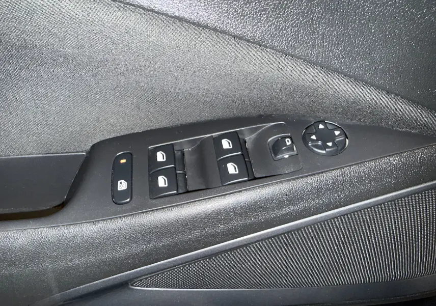 Gros plan sur la commande des vitres et rétroviseurs côté conducteur d’une Opel Crossland gris 2023.