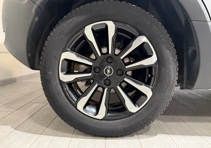 Gros plan sur la roue avant droite de l'Opel Crossland gris 2023 avec jante alliage noire et argentée au design moderne.