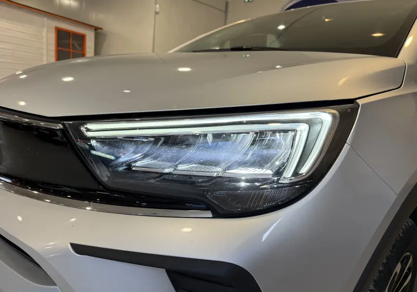 Gros plan sur le phare avant droit du SUV Opel Crossland gris 2023, mettant en valeur son design LED moderne.