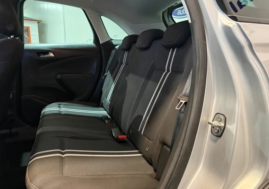 Vue intérieure côté droit des sièges arrière noirs avec bandes blanches d'un Opel Crossland gris 2023, porte ouverte.