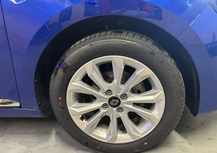 Gros plan sur la roue avant droite d’une Renault Clio 2024 bleu iron avec jante alliage au design moderne.