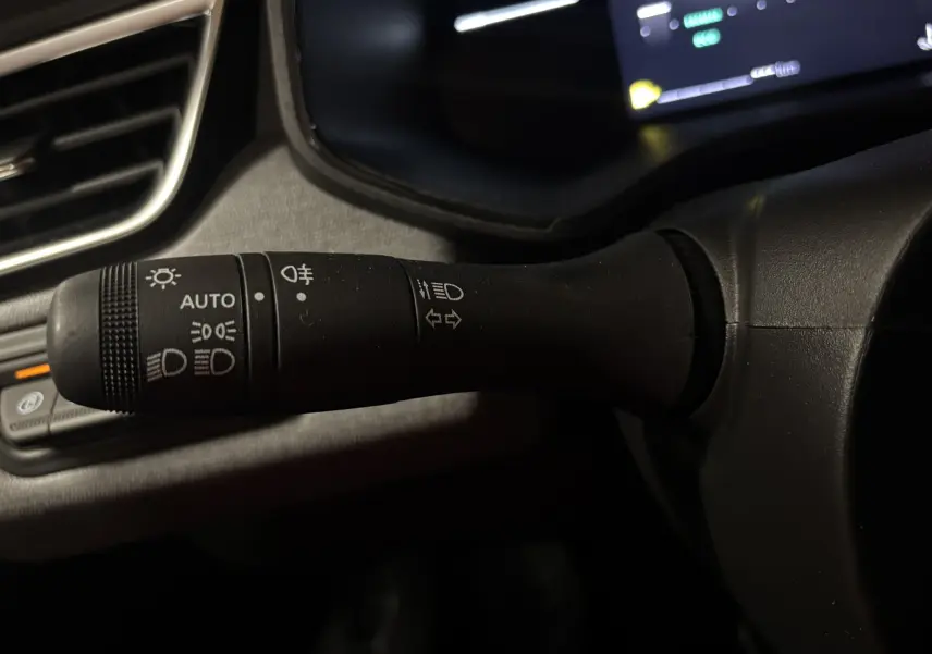 Gros plan sur la commande des feux et clignotants à gauche du volant dans l’habitacle gris noir de la Renault Clio TCe 90ch 2024.