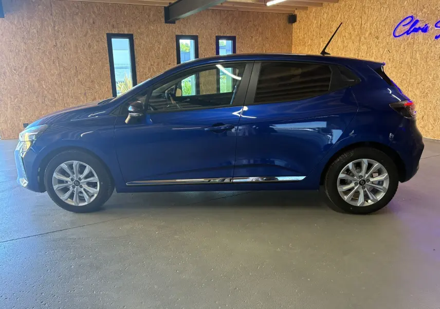 Profil droit d'une Renault Clio 2024 bleu iron, compacte cinq portes avec jantes alliage et vitres teintées.