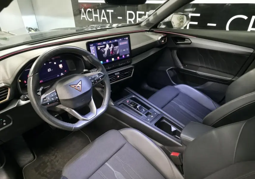 Vue intérieure côté conducteur du CUPRA Formentor 2021, tableau de bord noir avec éclairage d'ambiance rouge et écran tactile central.