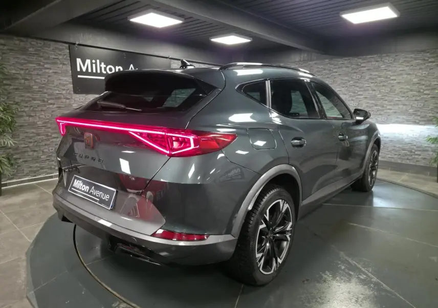 Vue 3/4 arrière droite d'une CUPRA Formentor gris caïman avec feux arrière LED en bandeau lumineux et jantes alliage 18 pouces.