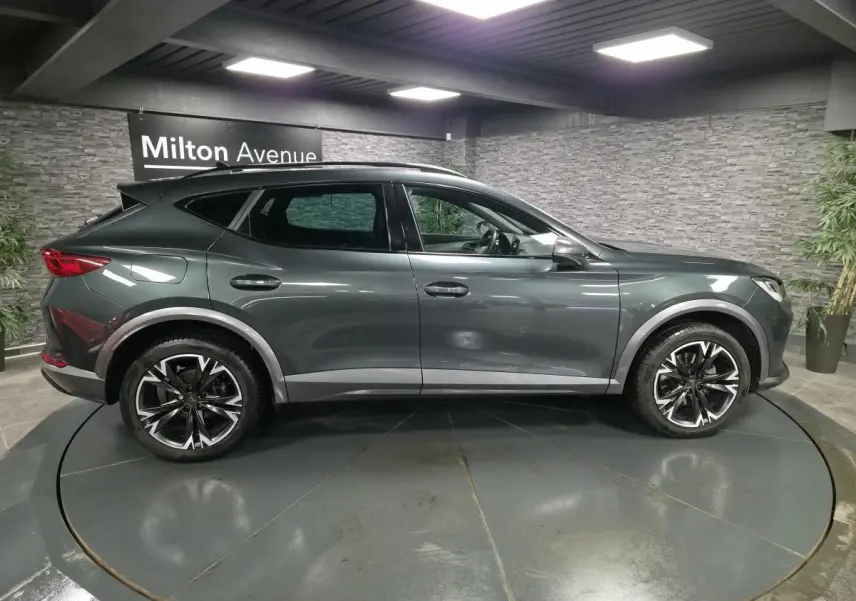 Vue de profil côté gauche d'un CUPRA Formentor gris Caiman avec jantes alliage noires et toit panoramique noir.
