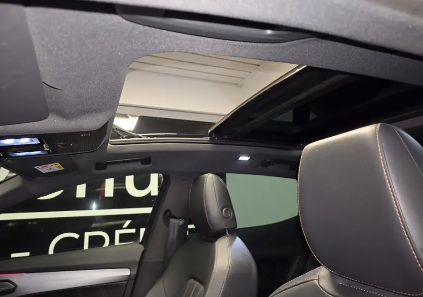 Vue intérieure du toit ouvrant panoramique et des sièges avant en cuir noir avec surpiqûres contrastantes du CUPRA Formentor gris.