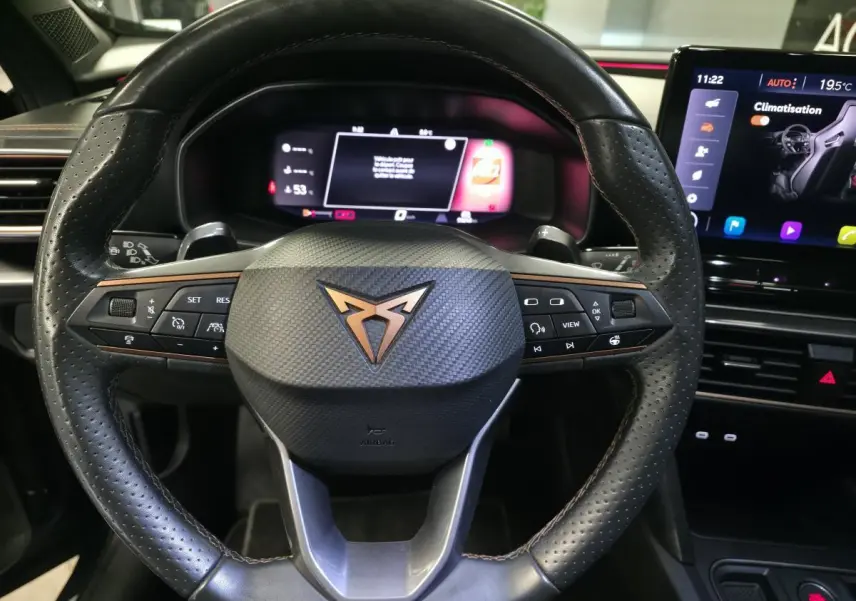 Vue rapprochée du volant sport noir perforé avec logo CUPRA cuivre et tableau de bord digital du Formentor gris.