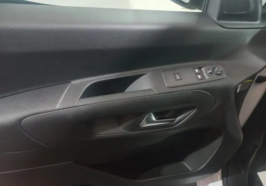 Vue intérieure du panneau de porte côté conducteur du Citroën Berlingo blanc, avec commandes électriques et poignée argentée.