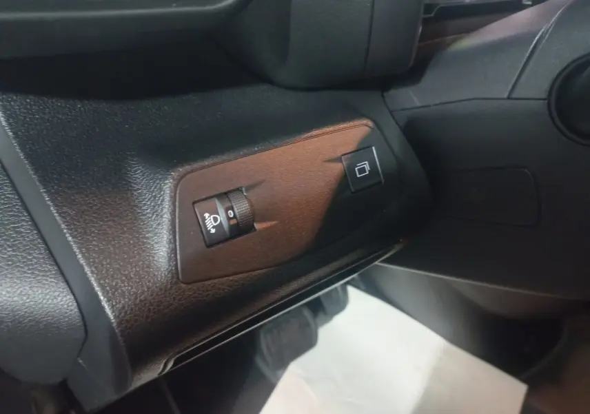 Détail intérieur côté gauche du tableau de bord du Citroën Berlingo XL blanc 2025, avec commandes de réglage des phares.