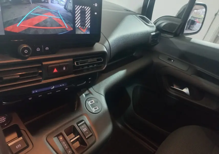 Vue intérieure côté passager du tableau de bord et console centrale du Citroën Berlingo blanc, avec écran multimédia affichant la caméra de recul.
