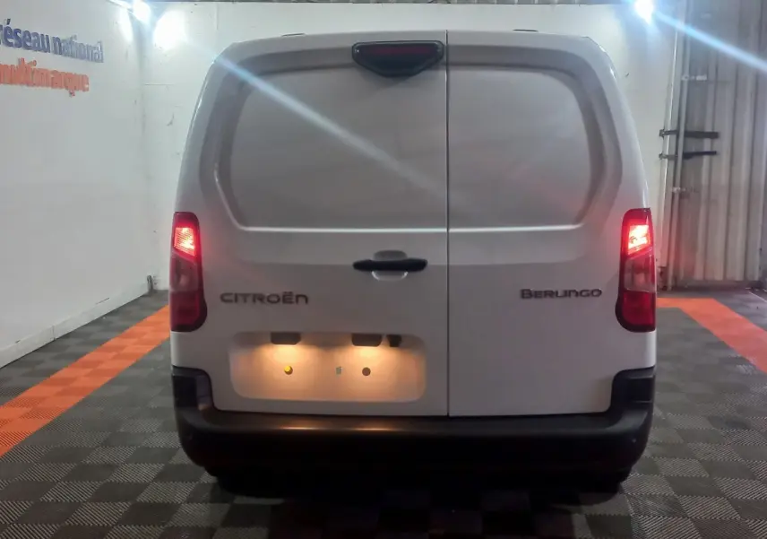 Vue arrière d’un utilitaire blanc Citroën Berlingo XL 2025 avec feux arrière allumés et plaque éclairée.