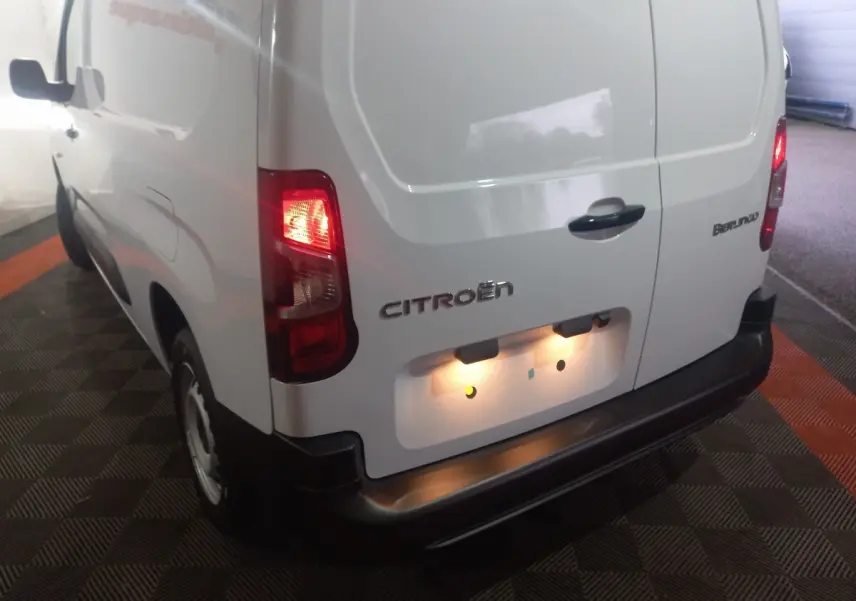 Vue 3/4 arrière droite du Citroën Berlingo blanc 2025 avec feux arrière allumés et porte arrière fermée.