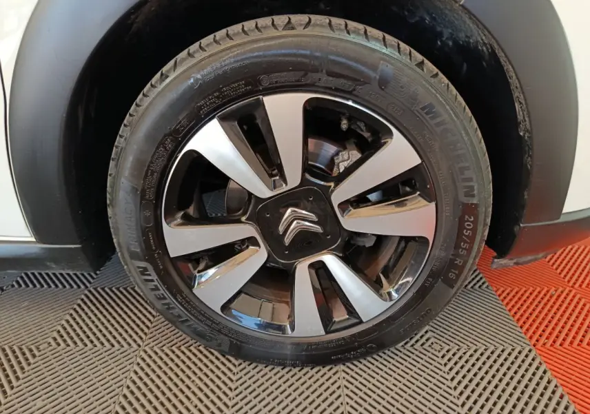 Gros plan sur la roue avant droite d'une Citroën C3 blanche, avec jante alliage bicolore et logo Citroën central.